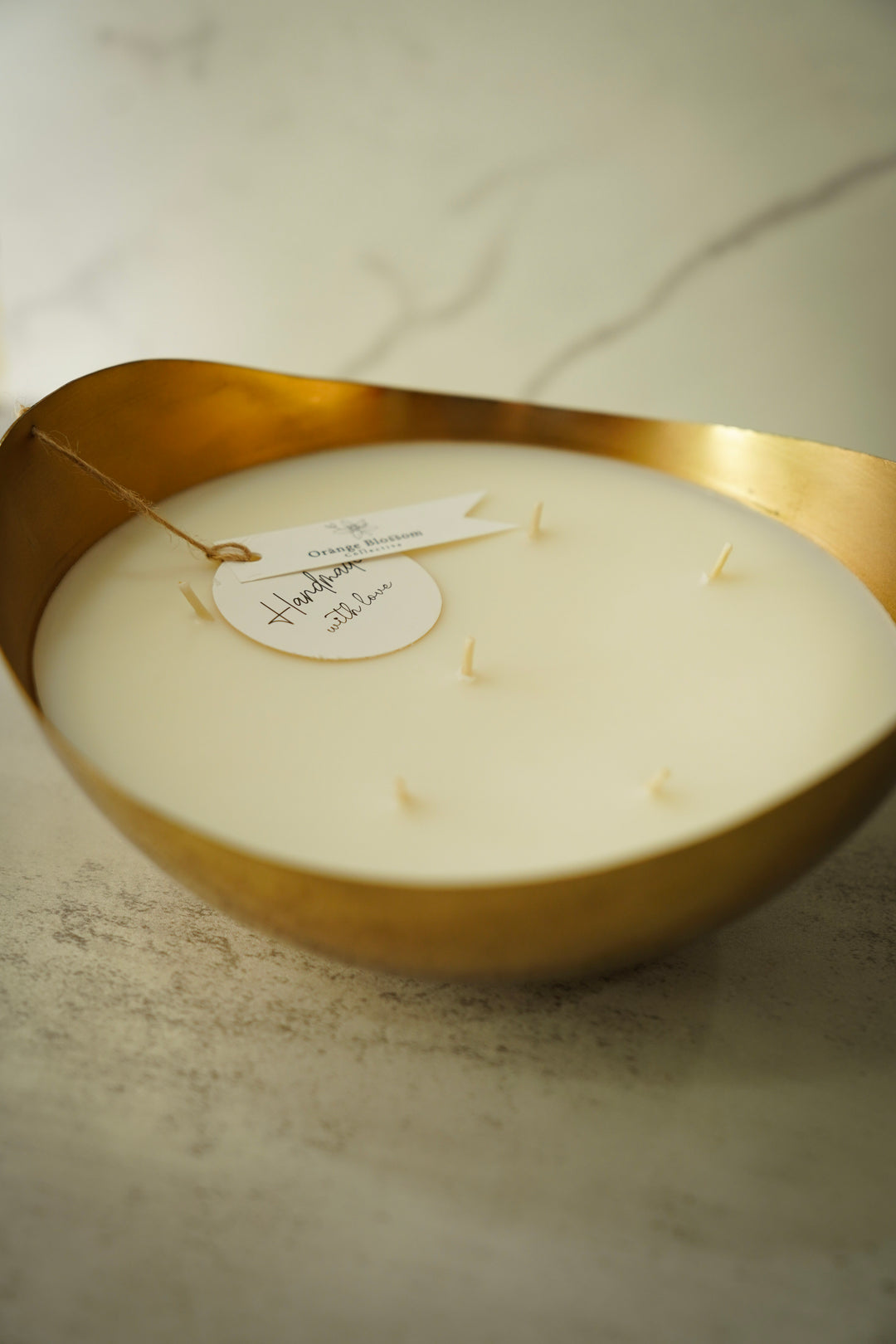 Multi-wick candle in gold organic-shaped bowl, close-up angled view