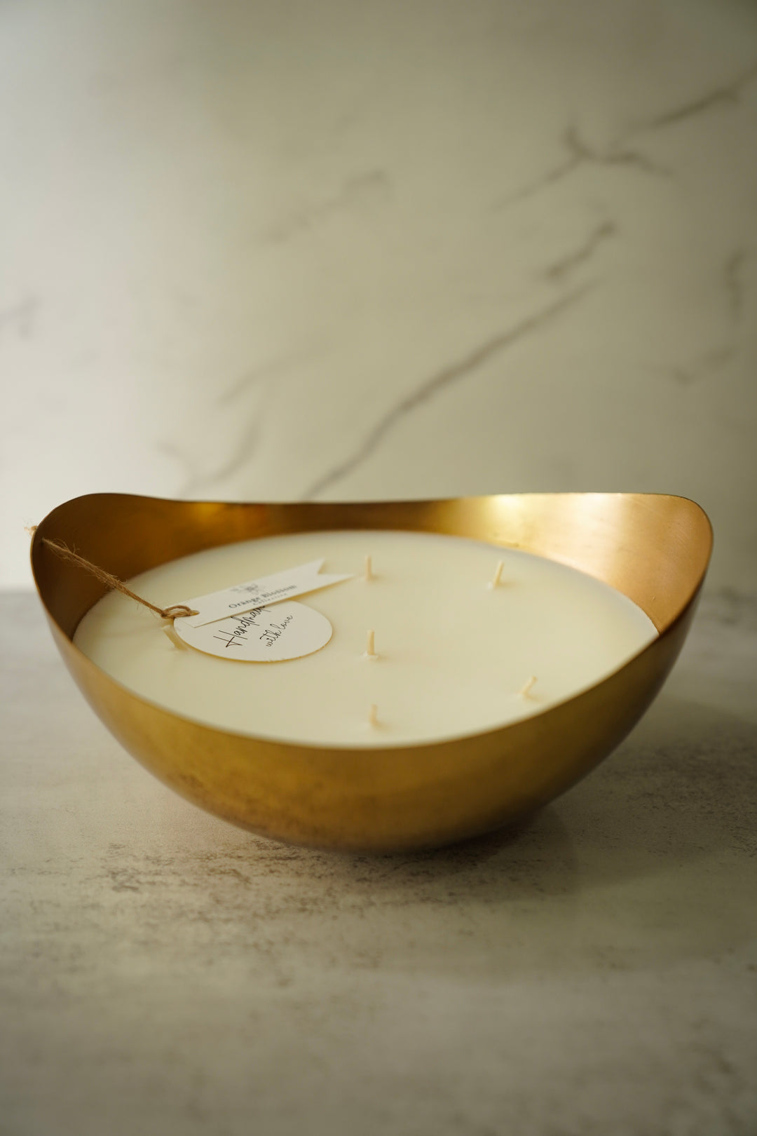 Orange Blossom Collective candle in gold organic-shaped bowl, front view on marble surface