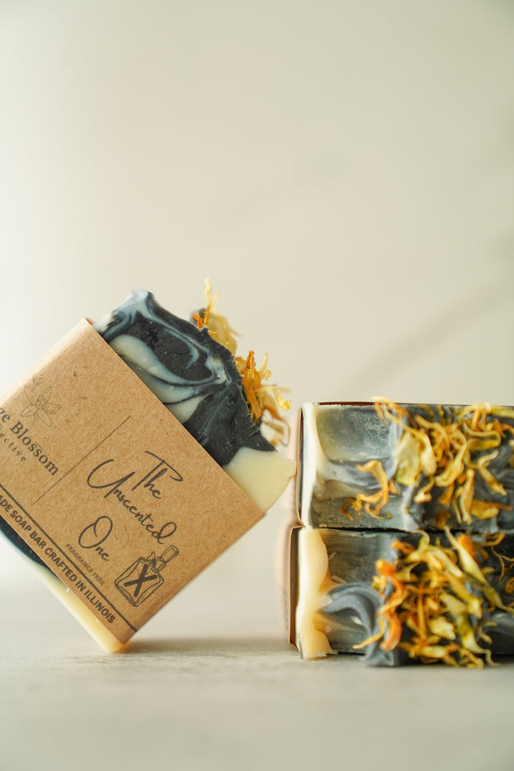 Orange Blossom Collective Unscented One soap bar tilted showing kraft label and natural ingredient texture