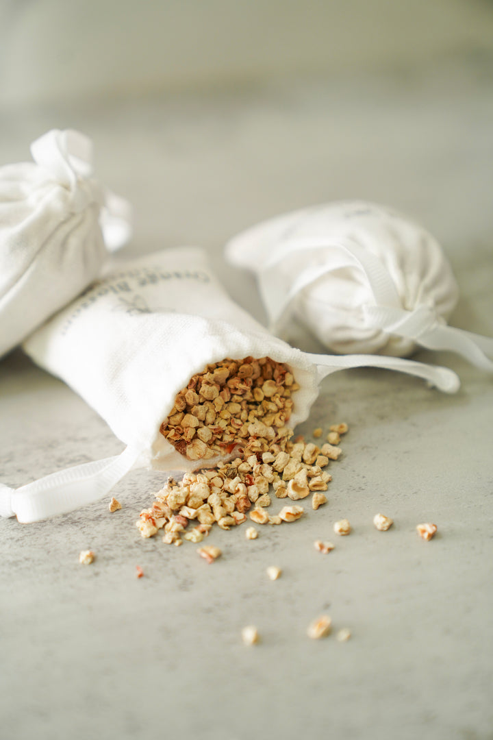 Orange Blossom Collective scented sachet tipped over showing dried botanical fragrance filling spilled out