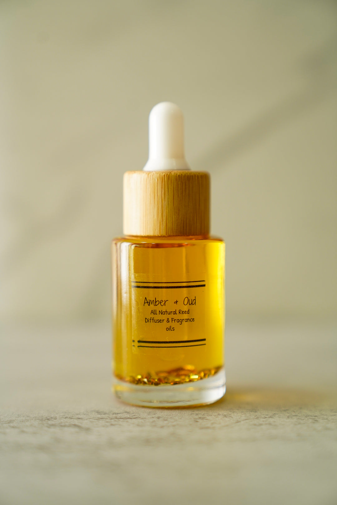 Orange Blossom Collective Amber & Oud car diffuser oil bottle with bamboo dropper cap on a neutral marble background