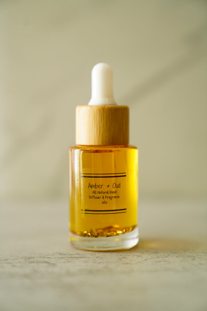 Orange Blossom Collective Amber & Oud car diffuser oil bottle with bamboo dropper cap on a neutral marble background