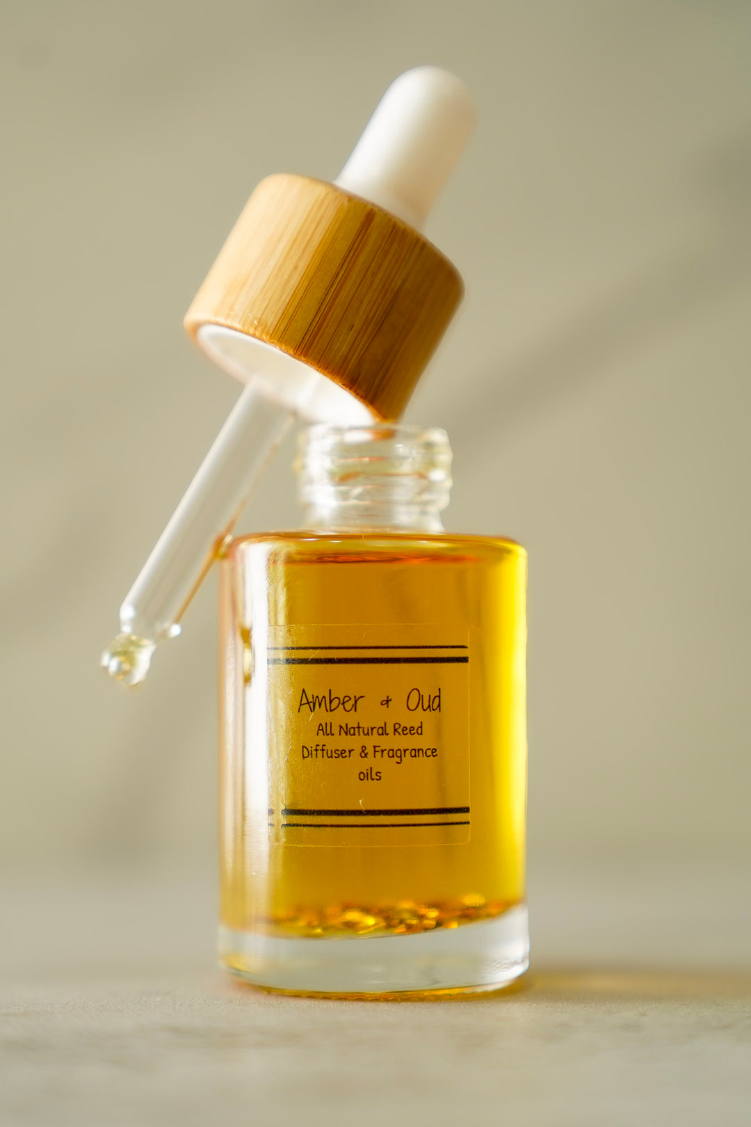 Amber & Oud all-natural car diffuser refill oil in a glass bottle with a wooden dropper cap, amber oil visible
