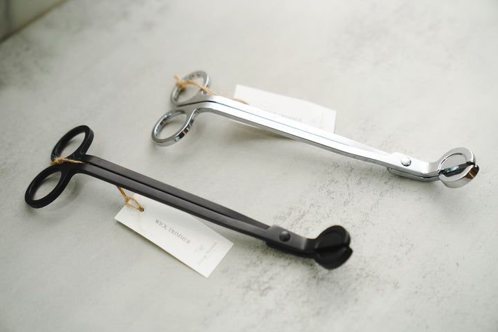 Two wick trimmers with brand tags side by side