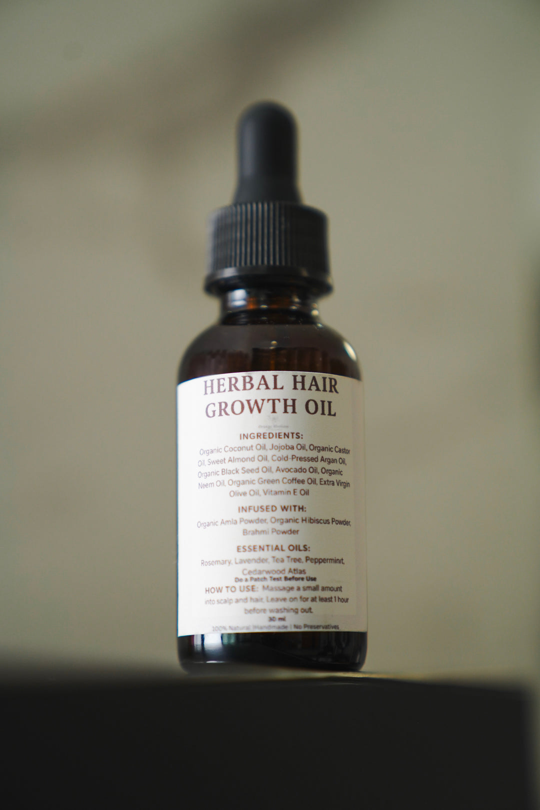Herbal Hair Growth Oil amber dropper bottle with ingredient label, close-up angled view