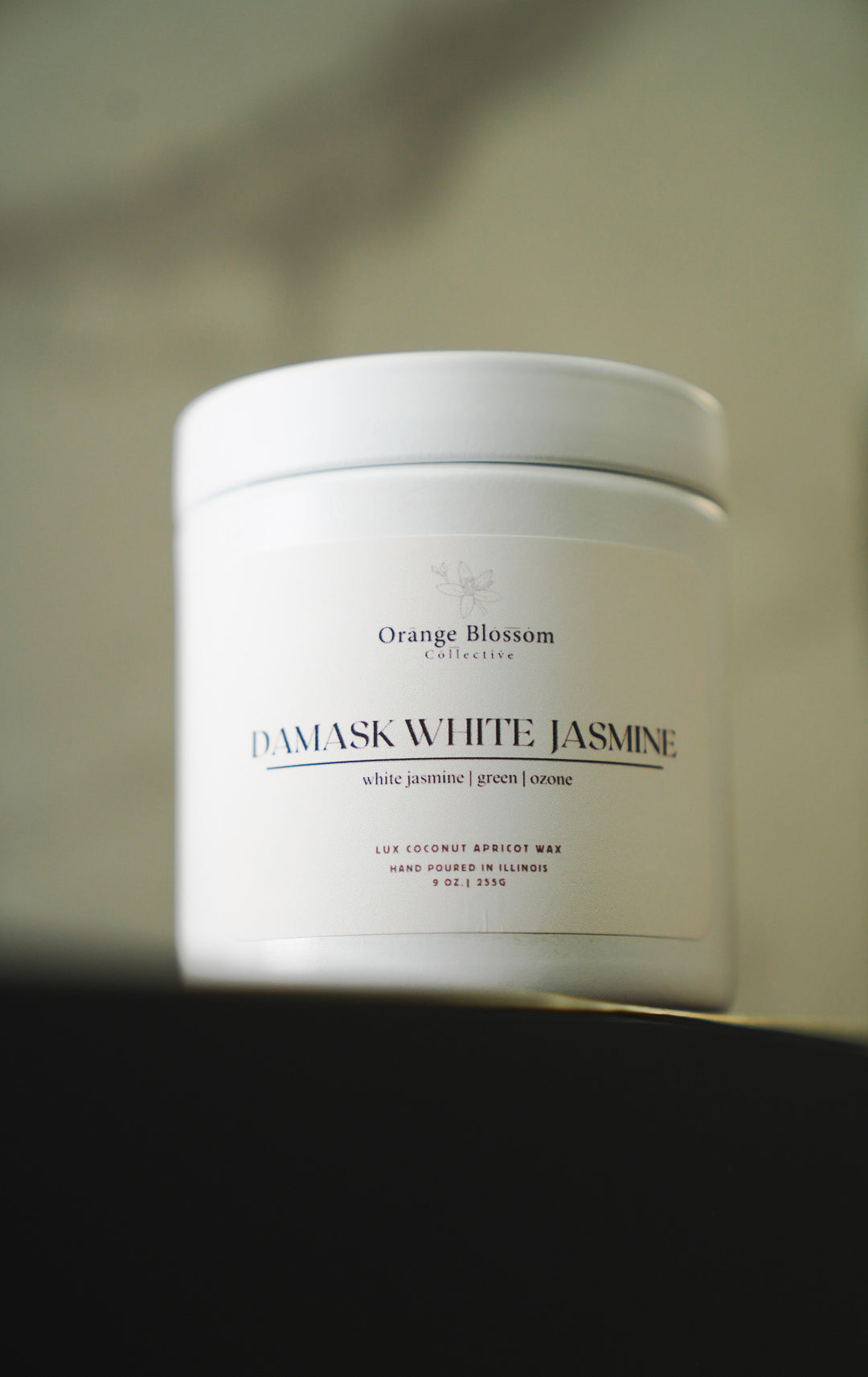 Damask White Jasmine candle jar on dark surface with warm lighting